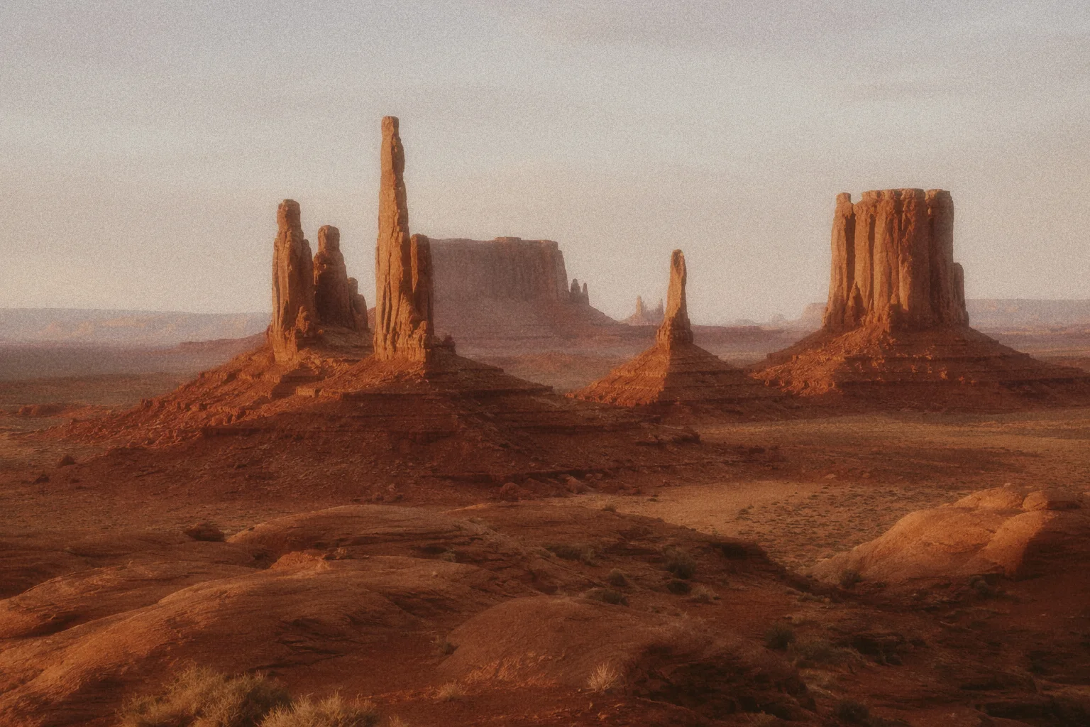 Desert landscape reference with towering sandstone buttes and mesas above a broad red-earth valley