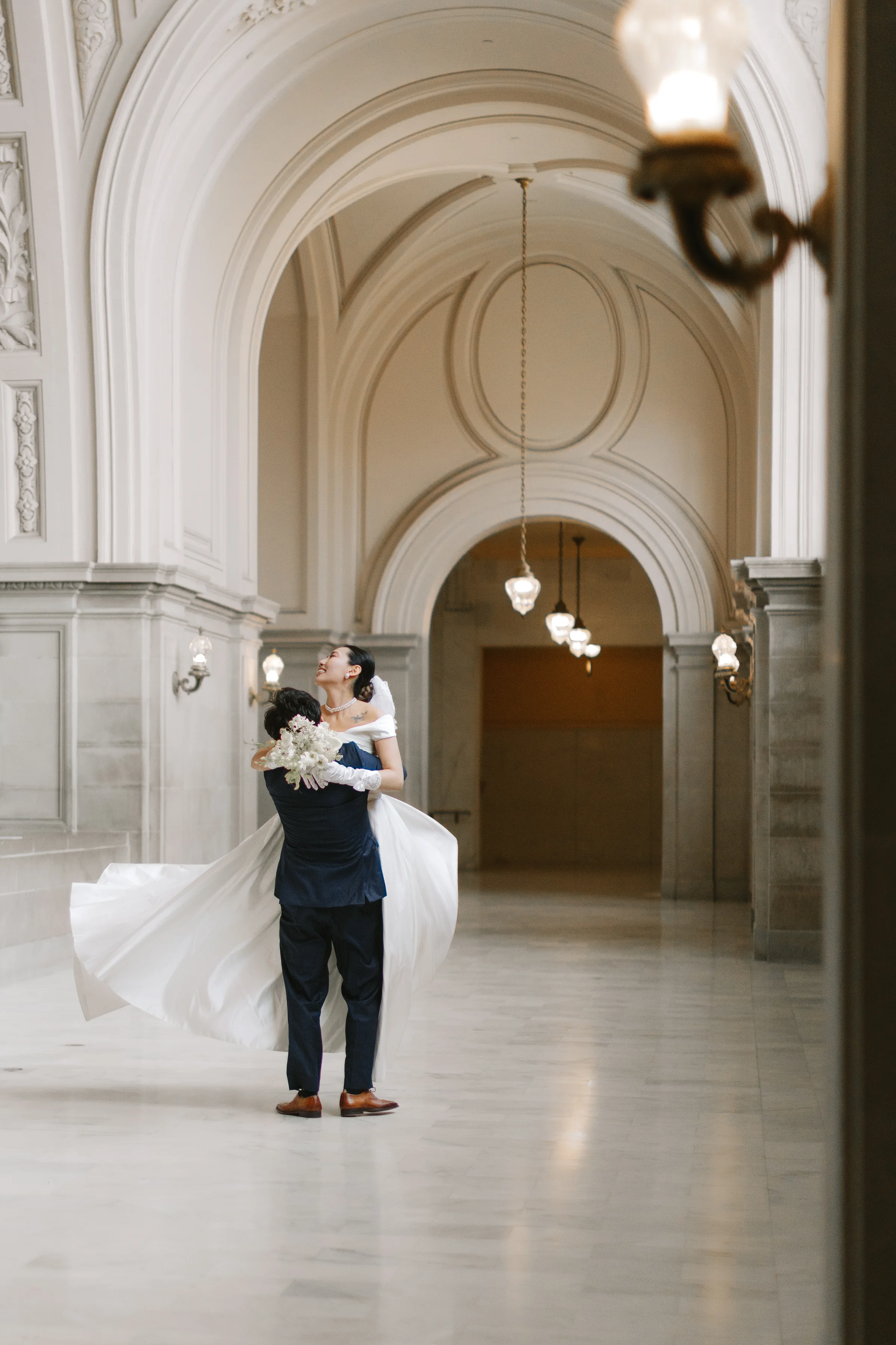 Groom lifting the bride in a grand arched marble corridor