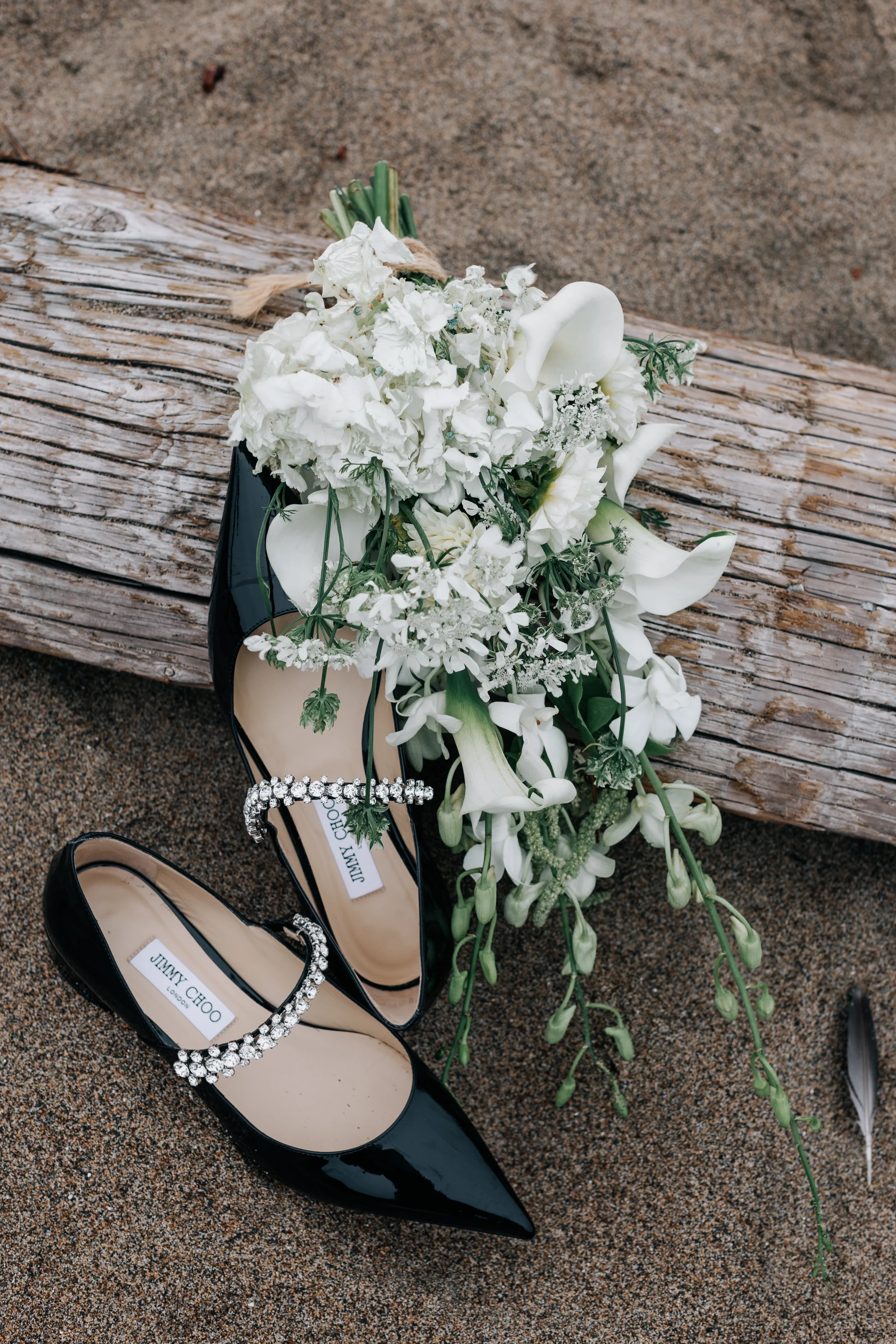 Pointed black heels and a white bouquet arranged on driftwood