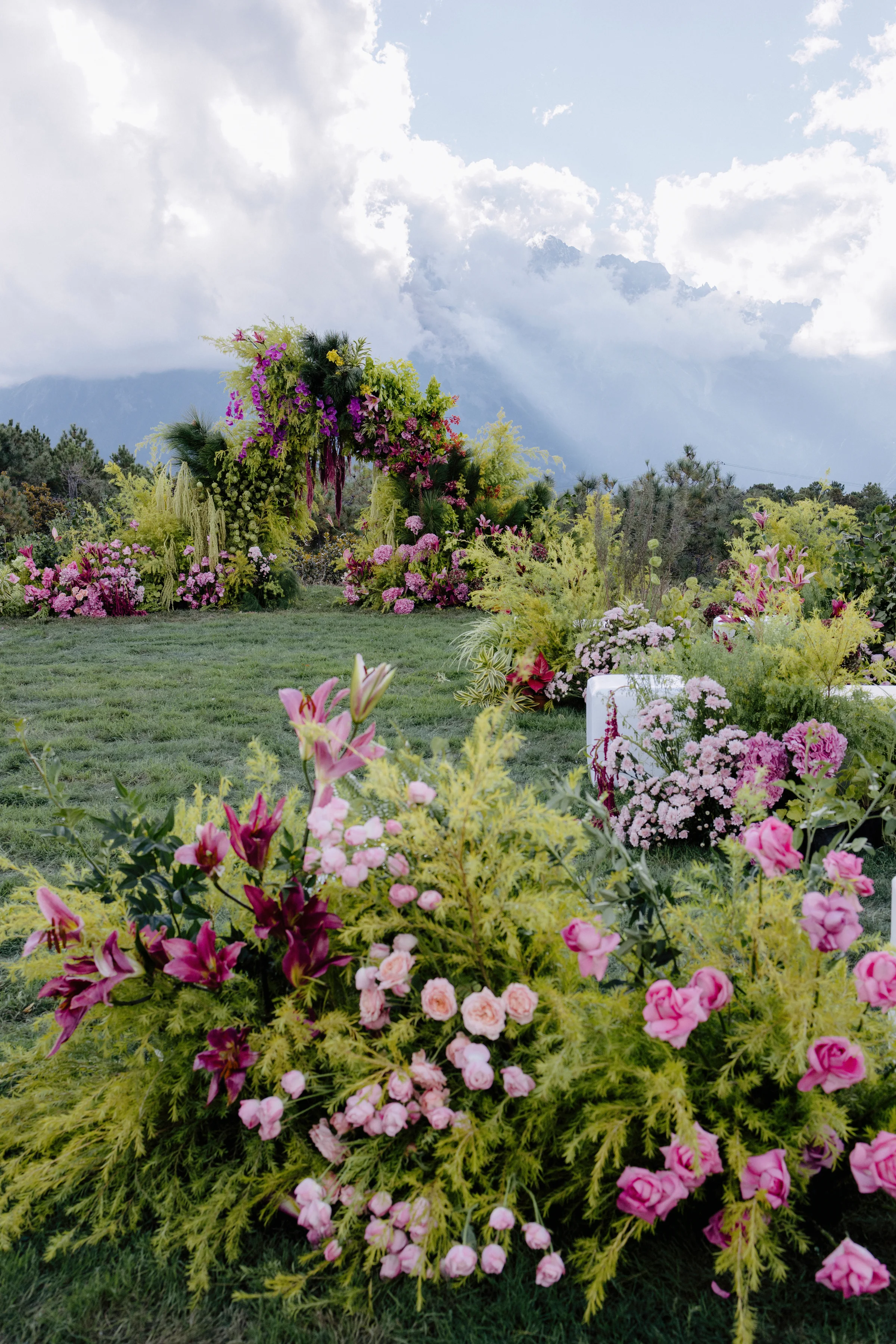 Lush pink and magenta ceremony floral installation with mountains beyond