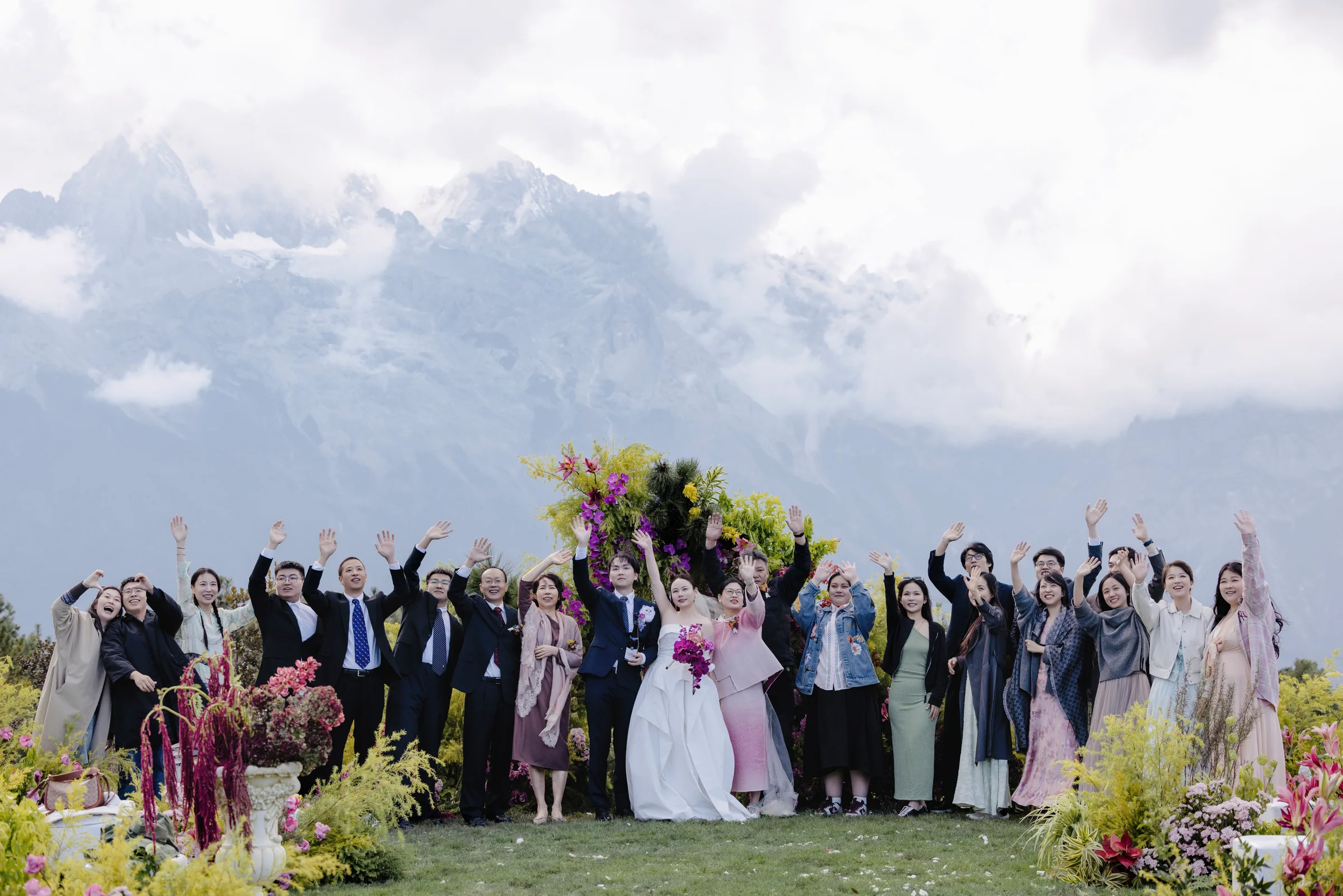 Large group portrait of the couple and guests before snow-capped peaks