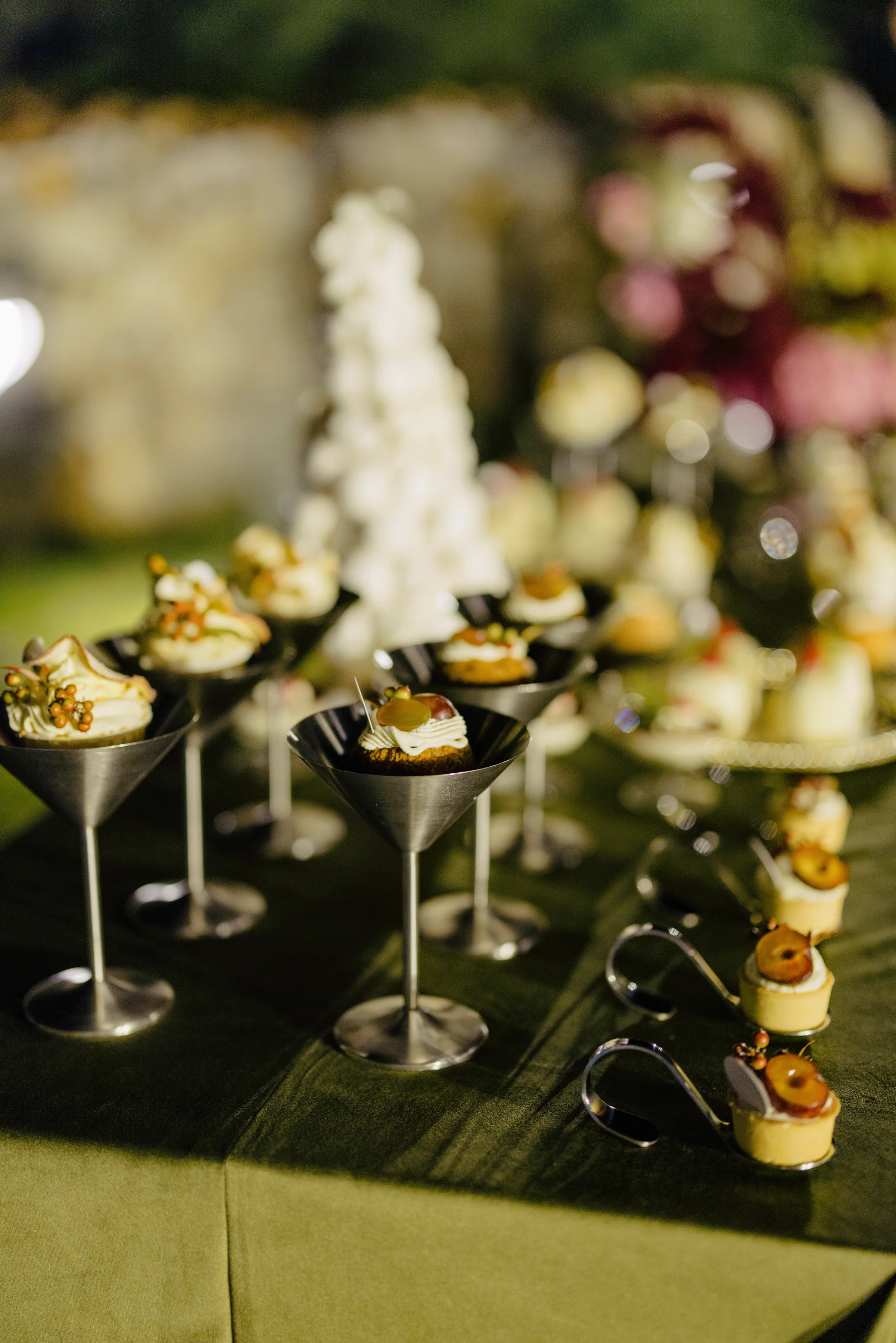 Dessert tower and canapés arranged on an olive-green linen table
