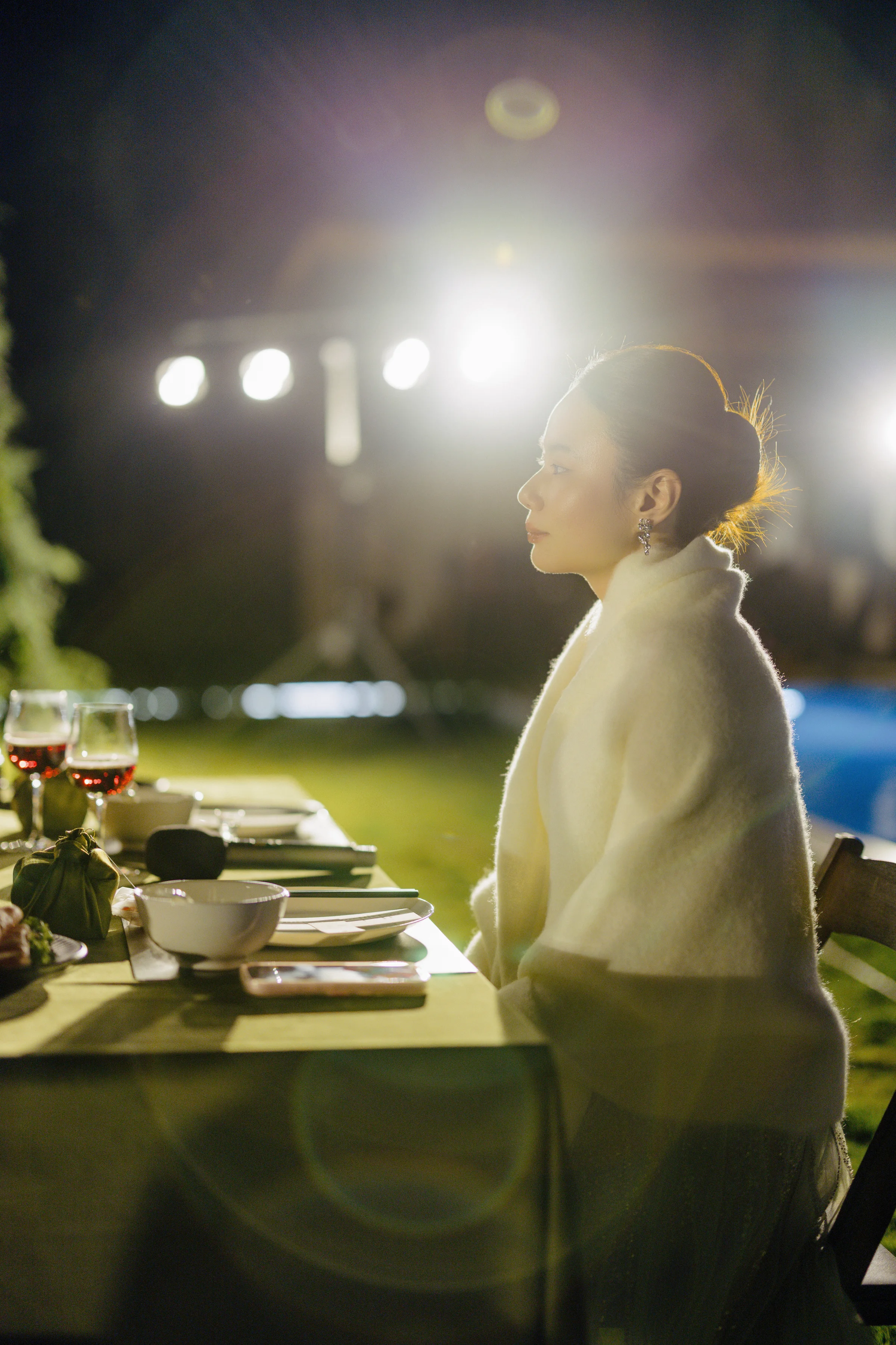 Bride in silhouette beside a candlelit reception table at dusk