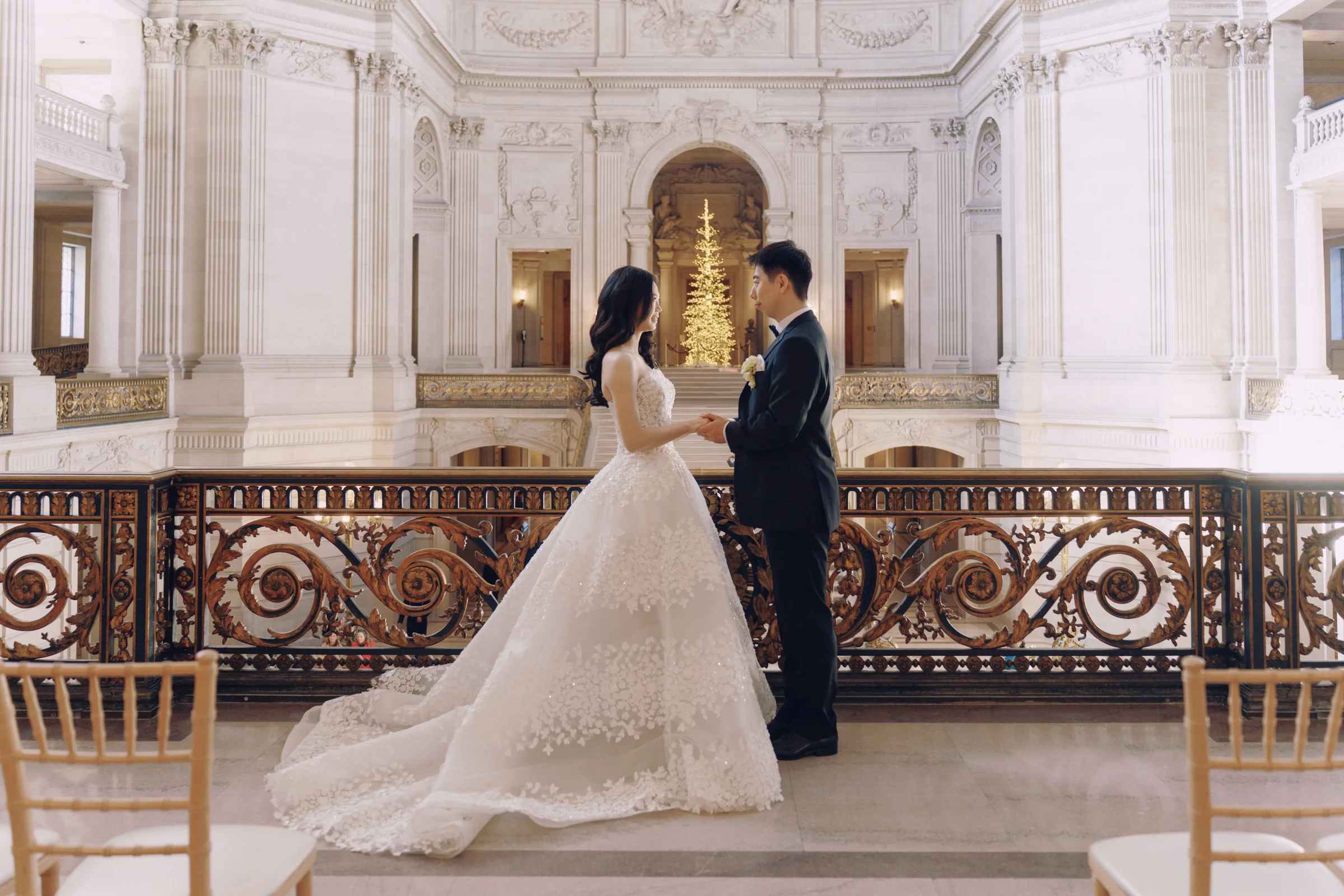 Couple embracing on the grand marble staircase, the bride in a full lace ballgown