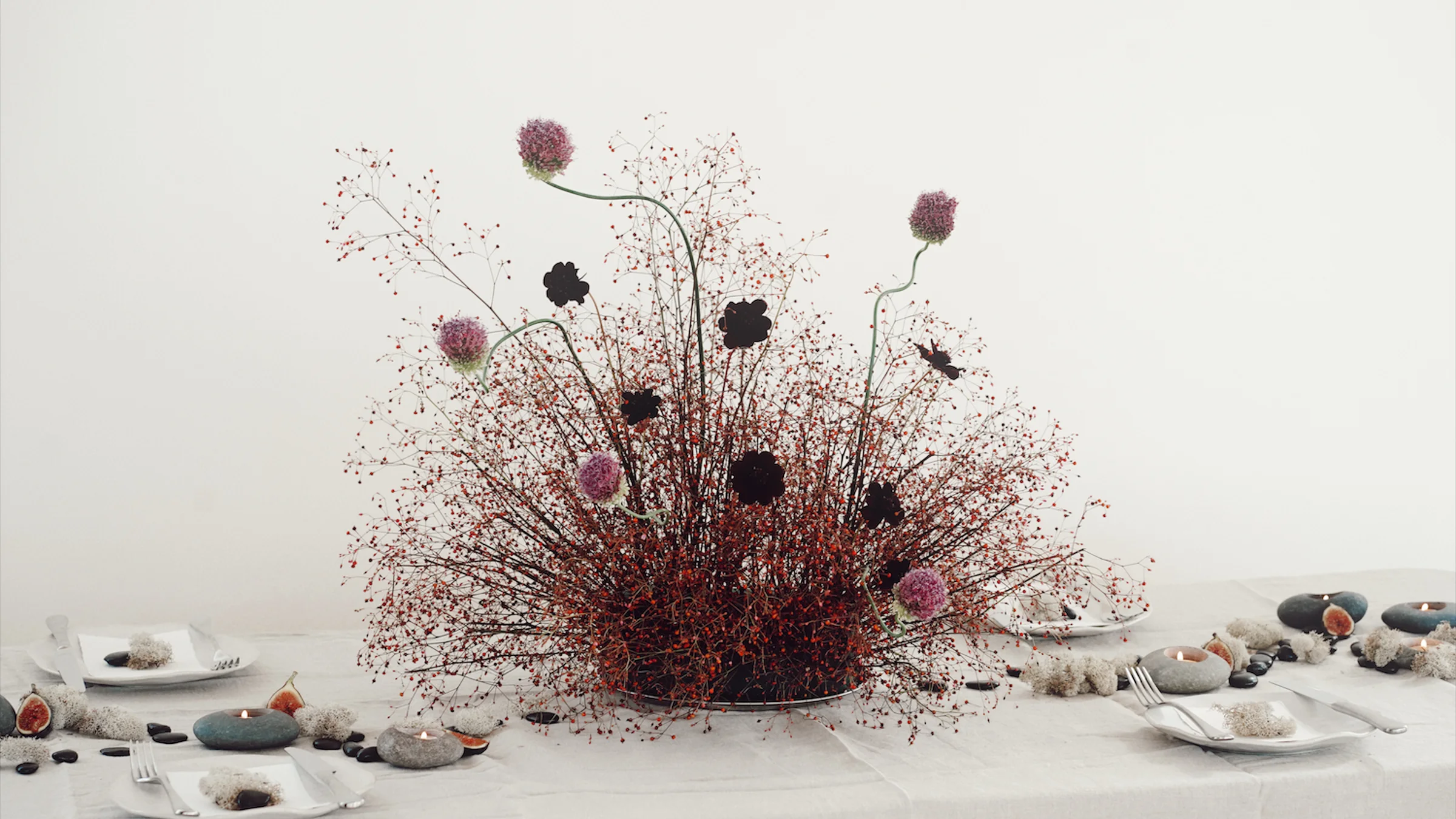 Sculptural baby's breath arrangement accented with purple and black alliums on a white table