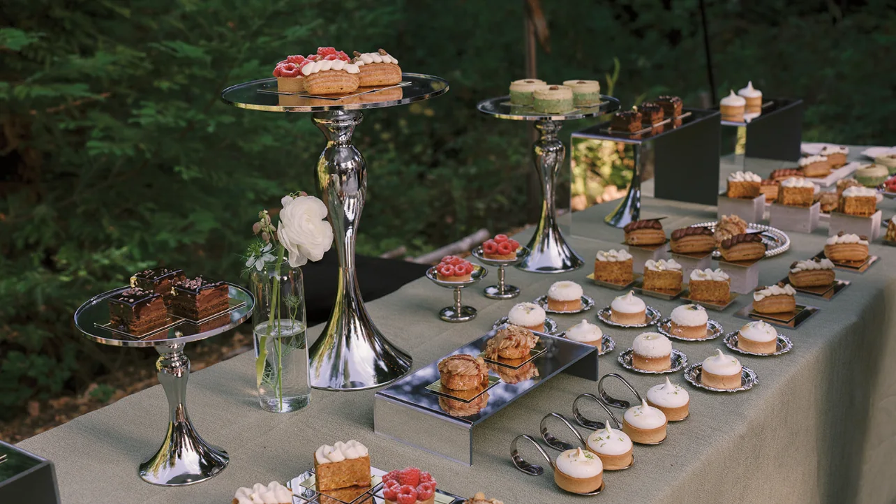 Outdoor dessert table with assorted pastries displayed on silver stands